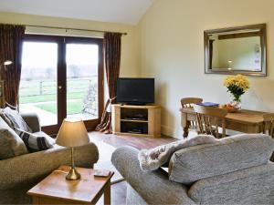 a living room with a couch and a television at Buttercup Cottage in Ripley