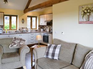 a living room with a couch and chairs in a kitchen at Buttercup Cottage in Ripley