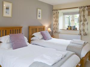 Duas camas brancas num quarto com uma janela em Newstead Cottage em Thornton Dale