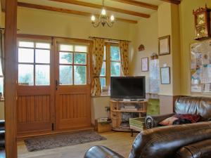 a living room with a couch and a television at Cefn Colwyn Barn - 28198 in Trefeglwys