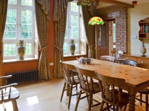 een eetkamer met een houten tafel en een aantal ramen bij Dove Cote House in Westleigh