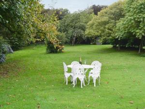a table with four chairs in a grass field at The Garden Cottage in Wrafton