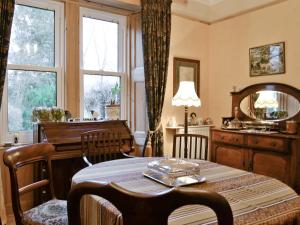 una sala da pranzo con tavolo e pianoforte di Ewes Schoolhouse a Bentpath