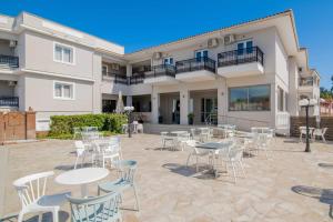 a patio with tables and chairs in front of a building at Karras Hotel in Laganas