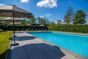 a swimming pool with an umbrella next to a swimming pool at Comfort Rooms by EuroParcs Buitenhuizen in Velsen-Zuid