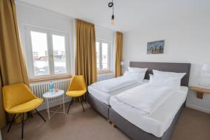 a bedroom with a large bed and two chairs at Logierhaus am Rathaus in Norderney