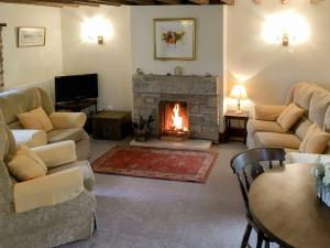 a living room with a fireplace and couches at Ellarbeck Cottage in Caldbeck