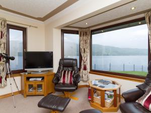 een woonkamer met een groot raam en een televisie bij Loch Duich Cottage in Inverinate