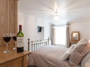 a bottle of wine sitting on a table next to a bed at One Beckside Cottage in Staithes
