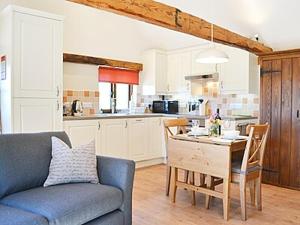 a living room with a couch and a table and a kitchen at Little Midge Barn in Ashburnham