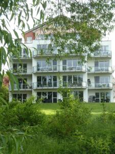 een groot wit appartementencomplex met balkons en bomen bij Fewo-Suite "Horizonte I"mit Boot in Ascheberg