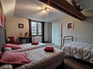 sypialnia z 2 łóżkami i czerwonymi poduszkami w obiekcie Aux Acacias w mieście Braye-sous-Faye