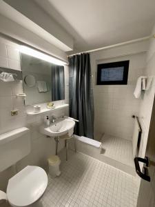 a white bathroom with a sink and a toilet at Hotel Brunnenhof in Bad Nauheim