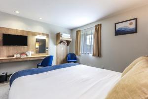 a hotel room with a bed and two blue chairs at Days Inn Peterborough in Peterborough