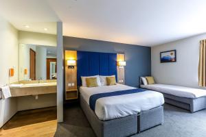 a hotel room with two beds and a bathroom at Days Inn Peterborough in Peterborough