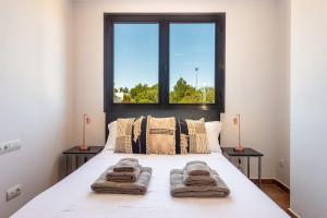 a bedroom with a white bed with two windows at Can Terra con piscina in Sant Josep de Sa Talaia