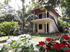 una casa con balcone e fiori rossi e bianchi di Blue Point Rest a Tangalle