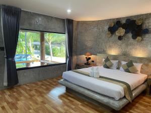 a bedroom with a large bed and a large window at Nao Ta Chuang in Thung Song