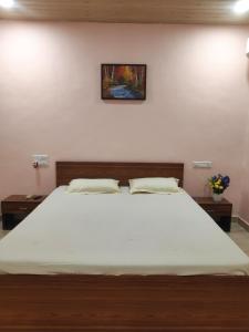 a bedroom with a large white bed with two tables at Soham Beach Resort, Diveagar in Diveagar