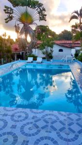 una gran piscina azul con 2 sillas blancas en Pousada Ancora, en Vera Cruz de Itaparica