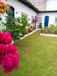 a house with pink flowers in the yard at Pousada Ancora in Vera Cruz de Itaparica