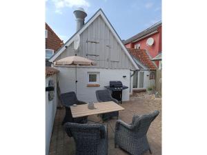 eine Terrasse mit einem Holztisch und Stühlen sowie ein Gebäude in der Unterkunft Ferienhaus Galerie No 5 in Garding