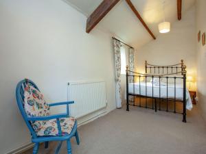 a bedroom with a bed and a blue chair at Swallows Swoop - Tbf in Crackington Haven