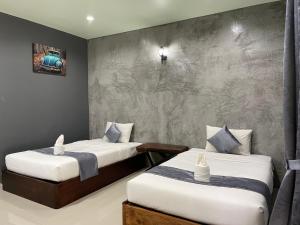 een slaapkamer met 2 bedden en een betonnen muur bij Nao Ta Chuang in Thung Song