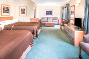a hotel room with two beds and a flat screen tv at Travelodge by Wyndham Kalispell in Kalispell