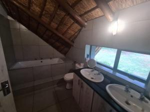 a bathroom with two sinks and a tub and a toilet at Mountain Villa House in Hartbeespoort