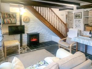 a living room with a fireplace and a staircase at Dawn Cottage in Portmellon