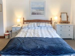 a bedroom with a bed with two dressers and two lamps at Dawn Cottage in Portmellon