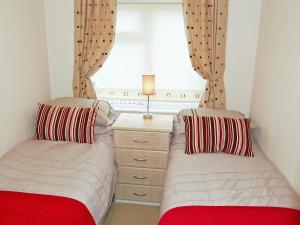 two beds in a room with a window at Rosewater Lodge in Saint Teath