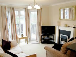 a living room with a couch and a television at Rosewater Lodge in Saint Teath