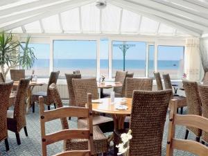 a dining room with tables and chairs and the beach at St Lawrence in St Brelade