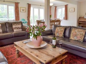 een woonkamer met een bank en een tafel met wijnglazen bij Holly Cottage in Pett