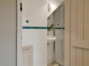 a white bathroom with a sink and a shower at Holly Cottage in Pett
