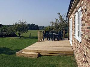 a wooden deck with a table and chairs on it at Holly Cottage in Pett