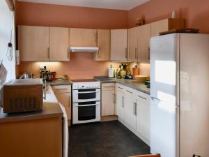 a kitchen with wooden cabinets and a white refrigerator at Low Fold Cottage in Stainforth