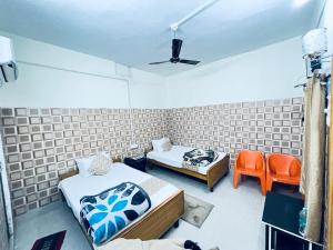 Habitación con 2 camas y 2 sillas de color naranja en HOTEL RAJGIR INTERNATIONAL, en Rajgir