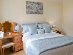 una camera da letto con letto con cuscini blu e scrivania di Russet a Ulrome