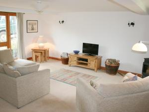 a living room with two chairs and a flat screen tv at Little Shelvin Farm Cottage in Luppitt