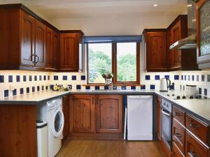 a kitchen with wooden cabinets and white appliances at Little Shelvin Farm Cottage in Luppitt