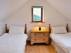 two twin beds in a attic bedroom with a window at Little Shelvin Farm Cottage in Luppitt