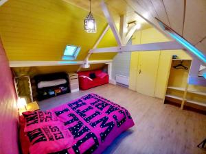 ein Schlafzimmer im Dachgeschoss mit einem rosa Bett und einem roten Sofa in der Unterkunft Maison de ville au cœur du quartier historique in Oloron-Sainte-Marie