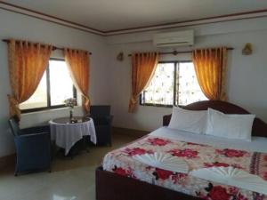 a bedroom with a bed and a table and windows at Angkor Ruby Guesthouse in Siem Reap