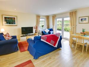 uma sala de estar com um sofá azul e uma televisão em Buzzard Cottages - 27940 em Cambusbarron