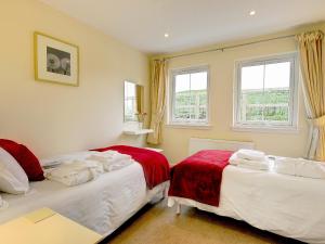 two beds in a room with two windows at Buzzard Cottages - 27940 in Cambusbarron