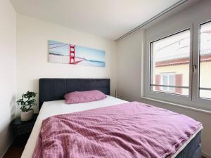 1 dormitorio con 1 cama con manta rosa y ventana en New building with balcony closecentrefreeparkingsmarttv, en St. Gallen
