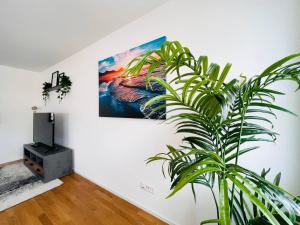 una planta en una habitación con una pintura en la pared en New building with balcony closecentrefreeparkingsmarttv, en St. Gallen